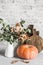 Pumpkin, bouquet of dry leaves, rustic chopping boards on the kitchen table. Autumn kitchen cosy home still life