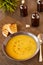 Pumpkin and carrot soup on a brown wooden table. Natural ecological yellow and orange soup puree in a ceramic plate. Healthy meals