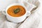 Pumpkin and carrot soup with cream,  seeds and rosemary herb on beige linen background.