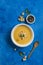 Pumpkin and carrot soup with cream and spinach with crackers on a classic blue background