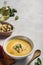 Pumpkin and carrot soup with cream and spinach with crackers on a white background