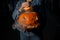 pumpkin with carved eyes and mouth and smoking from the inside in the hands of woman