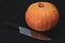 A pumpkin cooked to make a halloween lantern, and a sharp knife for making a face