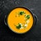 Pumpkin cream soup with pumpkin seeds in a black stone plate. Autumn menu. Diet. Top view.