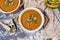 Pumpkin cream soup with seeds, sesame and rucola on a grey background. Autumn flat lay. Top view. Cozy photo