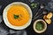Pumpkin cream soup with seeds and toast in a ceramic rustic bowl on a dark stone background. Winter warming soup. Top view, copy