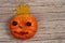 A pumpkin with eyes of chestnuts, lips of red hawthorn berries on a wooden background.