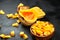 Pumpkin half, fresh pieces in wooden bowl on black background. Chopped raw butternut squash, selective focus