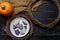 Pumpkin and Halloween cookies on white plate, sackcloth on black wooden background. Hallooween trick or treat concept.