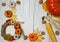 Pumpkin, handmade wreath, walnuts and corn cobs, textile pumpkins and autumn leaves on a light wooden background.