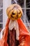 Pumpkin head scarecrow decorating home exterior in Halloween season.