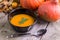 Pumpkin hokkaido soup in black bowl on natural wooden table.