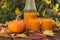 Pumpkin juice in glasses and bottles and pumpkin fruit on a wooden table.