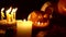 The pumpkin lantern on black background among candles dolly camera movement.