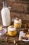 Pumpkin milkshake in glass jar with whipped cream, toffee, walnut and honey cookies. Bottle of milk. Dark wooden