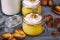 Pumpkin milkshake in glass jar with whipped cream, toffee, walnut and honey cookies. Bottle of milk. Gray napkin