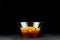 Pumpkin pieces in a deep transparent glass bowl on black background. Chopped butternut squash