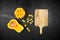 Pumpkin pieces, half of butternut squash, wooden bowl with chopped pumpkin, cutting board on black background, top view