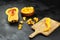 Pumpkin pieces, half of butternut squash, wooden bowl with chopped pumpkin, cutting board on black table