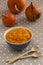 Pumpkin porridge in a bowl. Three orange pumpkins and two spoons. Gray Polka Dot Background