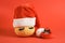 pumpkin in santa hat and false eyelashes and black little alarm clock on red background copy space