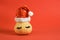 pumpkin in santa hat and false eyelashes on red background