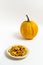 Pumpkin seeds in a saucer with orange pumpkin on a white background.