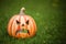 Pumpkin shaped ceramic candlestick on green grass. Funny Carved Pumpkin in the garden, halloween background