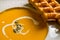 Pumpkin soup with belgian waffles on wooden background