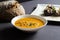 Pumpkin soup in a bowl with bread and roasted figs with goat cheese