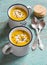Pumpkin soup in ceramic mugs on a wooden surface