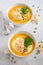 Pumpkin soup with cream, croutons, pumpkin seeds and parsley on a gray concrete or stone background.