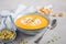 Pumpkin soup with cream, croutons, pumpkin seeds and thyme on a gray concrete or stone background