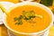 Pumpkin soup with green herb in white bowl on table in cafe