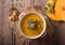 Pumpkin soup and organic pumpkins on wooden table. Seasonal autumn food - Spicy pumpkin soup in bowl.