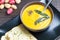 Pumpkin soup with sage leaves in brown ceramic soup plate with garlic bread.