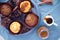 Pumpkin spice cupcake with buttercream and pumpkin sirup next to muffin on concrete grey round tray on blue napkin