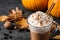 Pumpkin spice latte with whipped cream and cinnamon stick in glass cup on grey table. Space for text