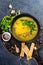 Pumpkin and vegetables cream soup with pumpkin seeds, slices of bread and parsley over a dark background with Space for text.