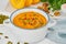 Pumpkin vegetarian cream soup with walnuts, side view on light background closeup
