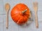Pumpkin , wooden fork and spoon on gray tablecloth