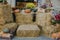 Pumpkins and autumn flowers in cobweb on hay bale, rustic festive decoration of european city street. Halloween street decor.