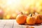 Pumpkins and autumn leaves on white wooden table, blurry background with copy space