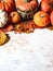 Pumpkins border of various sizes and colors and different dry autumn leaves on a marble background Copy space