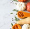 Pumpkins border of various sizes and colors and different raw herbs and spices on a marble background. Copy space