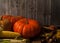 Pumpkins, corn, apples, walnuts and chestnuts, autumn leaves on a wooden background.