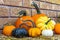 Pumpkins and gourds with twisting stems arranged on wooden porch