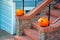 Pumpkins on orange or adobe red brick staircase with hand rails and metal poles with suburban wooden house exterior