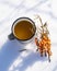 Punch with sea buckthorn berries in an iron white mug in the snow. Sea buckthorn twigs with tea