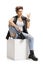 Punk girl sitting on a cube and making a rock hand gesture